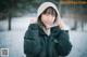 A woman wearing a black jacket and a white hat in the snow.