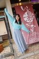 A woman standing in front of a building with her arms outstretched.