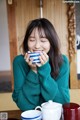 A woman sitting at a table with a cup of tea.