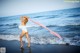 A woman in a white bathing suit standing on the beach.