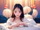 A girl laying on a bed with white pumpkins behind her.