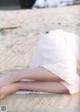 A woman in a white dress laying on the sand.