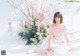 A woman sitting on the ground in front of a bunch of flowers.