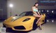 A woman in a bikini sitting on a yellow sports car.