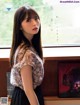 A woman standing in front of a window next to a book shelf.