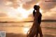 A woman standing on a beach looking up at the sky.