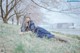 A woman in a blue dress laying in the grass.