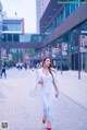 A woman in a white dress is walking down the street.