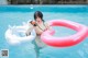 A woman in a bikini holding an inflatable ring in a pool.