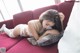 A woman laying on a red couch with a pillow.